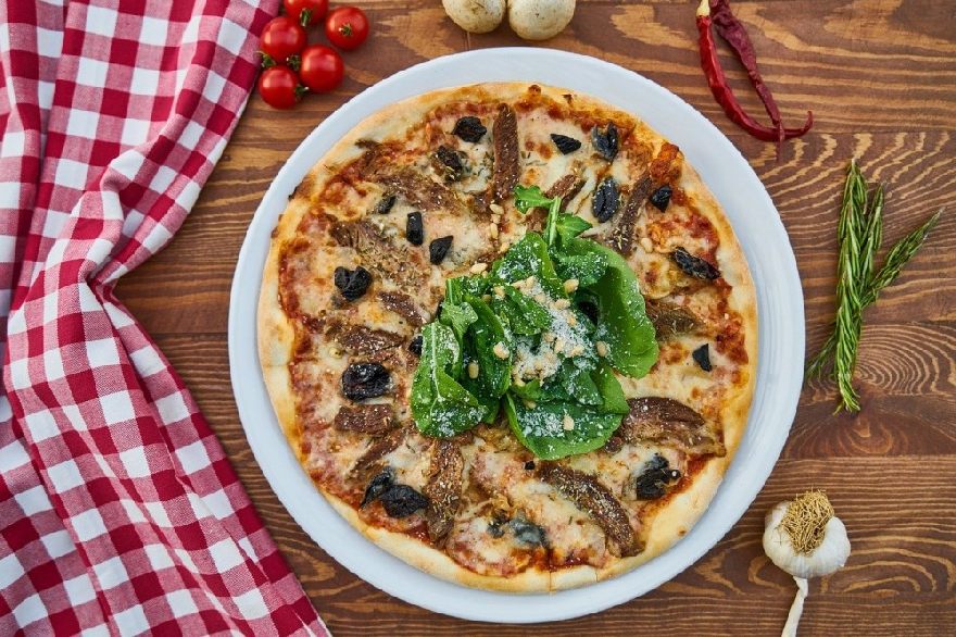 Leckere frische Steinofen, Holzofen Pizza auf einem Bunten Tisch eingerichtet wie bei der Pizzeria Forno mit leckeren italienischen Steinofen Essen mit Lieferservice in Bielefeld.